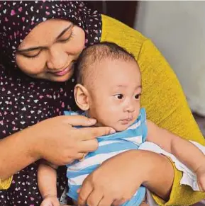  ?? [ FOTO NIK ABDULLAH NIK OMAR / BH ] ?? Nur Syazwani Akmal bersama anaknya ketika ditemui di rumahnya di Kampung Belukar, Tumpat, semalam.