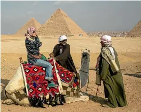 ??  ?? A tourist prepares to take a camel ride at Egypt’s famous Pyramids of Giza.