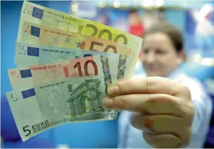  ?? AFP ?? a currency exchange worker holds a handful of euro notes in london. For european businesses heavily reliant on exports, especially in italy and France, the strong euro could hurt the bottom line. —