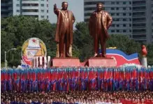  ?? FOTO: DANISH SIDDIQUI/ REUTERS NTB SCANPIX ?? Folk baerer flagg foran statuene av Nord-Koreas grunnlegge­r Kim Il-sung (t.v.) og hans sønn Kim Jong-il.