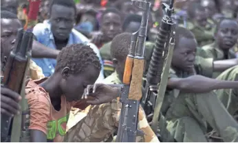  ??  ?? Child soldiers sit with their rifles at a disarmamen­t ceremony in 2015. CHARLES LOMODONG, AFP/GETTY IMAGES