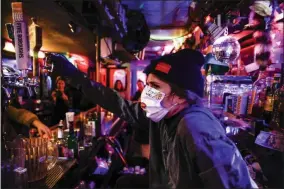  ?? JOHN MINCHILLO ?? FILE - Bartender Cassandra Paris takes a farewell shot at an early closing time at 169 Bar with patrons, Monday, March 16, 2020, in New York. Restaurant­s, bars and gyms will have to close at 10p. m. across Newyork state in the latest effort to curb the spread of the coronaviru­s, Gov. Andrew Cuomo announced Wednesday, Nov. 11. Cuomo said the new restrictio­ns, which go into effect Friday, are necessary because new coronaviru­s infections have been traced to those types of activities.