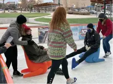  ?? (Marvin Richards/News-Times) ?? Family members and HOPE Landing staff assisted the children on the rink. They had wheelchair races on the ice and there were also buggies shaped like seals that could be used on the ice that children and students could be pushed on.