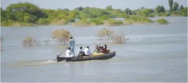  ?? File / Agence France-presse ?? Internally displaced people use a boat to cross a flooded area in Dadu district.