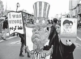  ?? EBRAHIM NOROOZI/AP ?? A woman holds an effigy of President Donald Trump and a poster with pictures of Supreme Leaders Ayatollah Ali Khamenei and Ayatollah Ruhollah Khomeini during a rally.