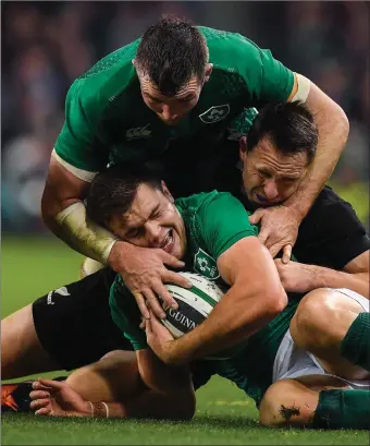  ??  ?? Jacob Stockdale of Ireland, supported by team-mate Peter O’Mahony, is tackled by Ben Smith of New Zealand during Saturday’s Guinness series internatio­nal match in the Aviva Stadium.