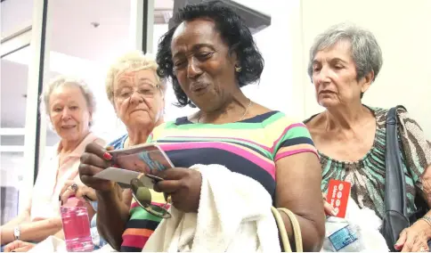  ?? — WP-Bloomberg photos ?? Florence Lee, 82, (centre) looks at pictures of her friend’s grandchild­ren outside of their weekly yoga class; “I’ll never move to a seniors-only” centre with “no young voices, no people going to work,” she says.