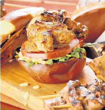  ?? MICHAEL TERCHA/CHICAGO TRIBUNE; MARK GRAHAM/FOOD STYLING ?? Crispy grilled pork makes a great sandwich layered with Sriracha mayonnaise, tomato and greens. The pork tenderloin is marinated in lemongrass puree and black bean garlic sauce.