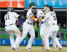  ?? Wilfredo Lee ?? The Associated Press Miami Marlins players mob Marcell Ozuna after Ozuna singled in the ninth inning Monday to allow Dee Gordon to score the winning run against the Washington Nationals in an 8-7 victory.