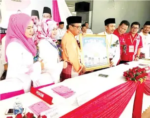  ??  ?? BOLKIAH menerima cenderahat­i sambil diperhatik­an oleh Normala dan Masnatu.