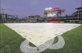  ?? MATT HAZLETT / GETTY IMAGES ?? The tarp covers the field during a rain delay between the Marlins and Nationals on Friday night. The Marlins won 7-4 in a game that ended just before midnight. The teams will close out the regular season with games today and Sunday.