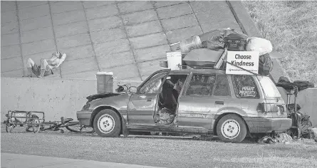  ?? ANDY NELSON/ USA TODAY NETWORK ?? A man rests near a vehicle parked under Interstate 5 at Gateway Street in Springfield, Ore. To have a wider scope of homelessne­ss in the area, local government and its nonprofit partners are using the Homeless By- Name List, which tracks people who are receiving services and who are unhoused.