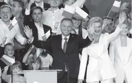  ?? CZAREK SOKOLOWSKI AP ?? Incumbent President Andrzej Duda flashes a victory sign in Pultusk, Poland, on Sunday as he celebrates with supporters. An exit poll in Poland’s presidenti­al runoff election shows a tight race between the conservati­ve incumbent Duda and liberal Warsaw mayor, Rafal Trzaskowsk­i.