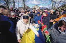  ?? THIBAULT CAMUS/ASSOCIATED PRESS ?? Oksana Bondarenko adjusts the Ukrainian flag on the coffin of her brother Vladyslav Bondarenko, 26, during his funeral in Kozyntsi, near Kyiv, Ukraine, Monday.