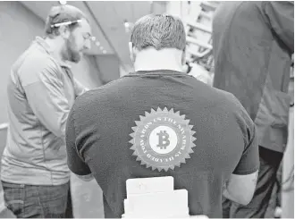  ?? Daniel Acker / Bloomberg ?? A trader wears a bitcoin shirt while working in the S&P 500 options pit last week at Cboe Global Markets in Chicago. Bitcoin’s underlying technology can work against its use by criminals.