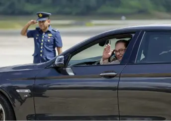  ?? — Bernama ?? Anwar waves to the press as the vehicle driven by Sultan Hassanal departs the RMAF base for Seri Perdana. photo