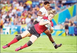  ??  ?? England’s Emily Scarratt (center), is tackled by Fiji’s Ana Naimasi (left), in the women’s Rugby Sevens match during the 2018 Gold Coast Commonweal­th Games at the Robina
Stadium on the Gold Coast on April 13. (AFP)