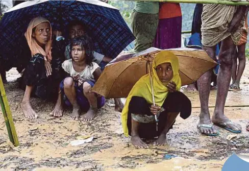  ??  ?? PELARIAN Rohingya berteduh dalam hujan di kem pelarian Balukhali, Bangladesh. - AFP