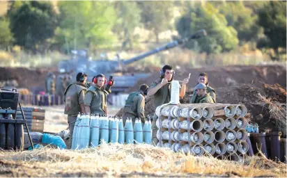  ?? (Noam Revkin Fenton/Flash90) ?? IDF ARTILLERY CORPS soldiers prepare shells to fire into Gaza as heavy rocket and missile barrages pounded Israel yesterday.