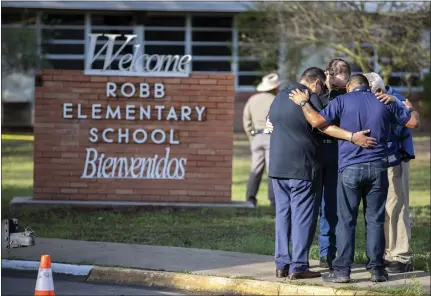  ?? PIERRE AGUIRRE — THE NEW YORK TIMES ?? Men pray outside Robb Elementary School in Uvalde, Texas, on Wednesday after Tuesday's mass shooting. Harrowing details began to emerge Wednesday of the massacre inside the school, as anguished families learned whether their children were among those killed by an 18-year-old gunman.