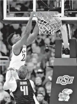  ?? AP Photo/Charlie Riedel ?? ■ Kansas’ Silvio De Sousa (22) gets past Oklahoma State’s Mitchell Solomon (41) to dunk the ball during the first half in Big 12 conference tournament game Thursday in Kansas City, Mo.