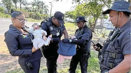  ?? ?? Members of a private security company with Nomalanga Msomi's baby after the three-month-old girl was found in long grass in Verulam.