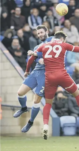  ??  ?? Ryan Tafazolli and Jason Naismith battle for a high ball against Scunthorpe.