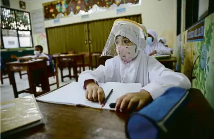  ?? ADI WEDA / EFE ?? Una nena a classe protegida amb mascareta i una pantalla en una escola de Jakarta