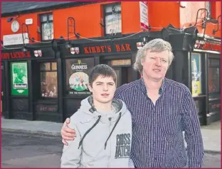  ??  ?? Mike Leane stands proudly outside their black and amber bar with his son Michael. “Everything in Ballyheigu­e rose out of Kirby’s,” says Mike.
