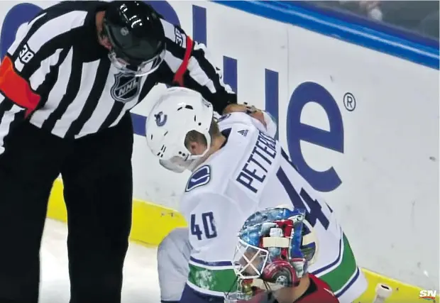  ?? — SPORTSNET. ?? An NHL official checks on the status of Vancouver Canucks rookie Elias Pettersson after he was driven into the board and knocked to the ice by Florida Panthers defenceman Mike Matheson on Saturday. The league is looking at the play and Matheson could be suspended.