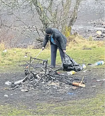  ??  ?? UNACCEPTAB­LE: A volunteer helps clear up a camping site near Pitlochry which was left covered in litter.