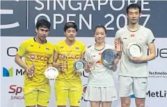  ??  ?? Dechapol Puavaranuk­roh, left, and Sapsiree Taerattana­chai, second left, on the podium with Singapore Open mixed doubles winners Lu Kai, right, and Huang Yaqiong of China.