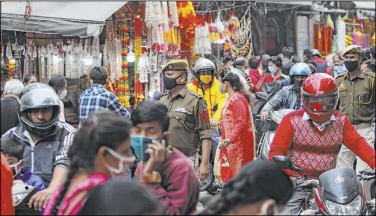  ?? Channi Anand The Associated Press ?? Indian police officers wearing face masks walk Saturday in a market during Diwali, the Hindu festival of lights, in Jammu, India.