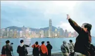  ?? REUTERS ?? Visitors take photos at the Kowloon waterfront facing Victoria Harbor that overlooks prime property of Hong Kong. Ultra-rich people grew in Chinese mainland and Hong Kong in 2016.