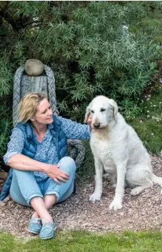  ??  ?? Garden owner Jackie Michelmore sits against one of The Lookout’s many coastal features, with labradoodl­e Archie.