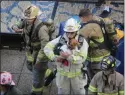  ??  ?? A Cortland County firefighte­r holds “Ariel”, the first dog to participat­e in the CNY Memorial Stair Climb in honor of the working dogs who assisted during 9/11.