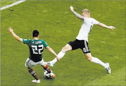  ?? Michael Probst ?? The Associated Press Mexico forward Hirving Lozano, left, scores past Germany midfielder Toni Kroos in a World Cup match Sunday in Moscow, sending Mexico to a 1-0 victory. “It’s definitely the best goal I’ve ever scored in my entire life,” Lozano said.