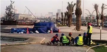  ?? ?? Water works: labourers toil away on the Corniche, a promenade by the sea front