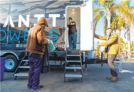  ?? DON BOOMER ?? Jordan Verdin holds the door for a homeless man who was taking advantage of one of the six mobile showers in the Humanity Showers trailer in Oceanside on Wednesday. Javier Blea (center) cleans the shower between clients.