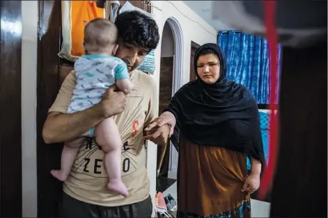  ?? (AP/Altaf Qadri) ?? Mohammad Nabi holds his 7-month-old daughter, Bahar, on Aug. 13 as he helps his wife, former Afghan policewoma­n Khatera Hashmi, inside a rented accommodat­ion in New Delhi. Last year, Hashmi was attacked on her way home from work in Ghazni province, Afghanista­n. She was shot multiple times and her eyes were gouged out.