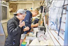  ??  ?? Harley Newton, left, a veterinari­an and head of aquatic health at the Wildlife Conservati­on Society at the New York Aquarium, and Lisa Hoopes, a nutritioni­st at the Georgia Aquarium, work on blood samples from a shortfin mako aboard the Ocearch shark...