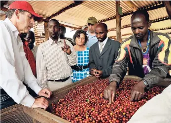  ?? PHOTO BY RICCARDO GANGALE ?? Through links with the Presidenti­al Advisory Council, Starbucks CEO agreed to distribute Rwandan coffee. In photo, Howard Schultz (left), chairman, president and CEO, Starbucks Coffee Company, and Harriet Lamb (centre), executive director, Fairtrade Foundation with coffee farmers at a coffee washing station at Dukunde Kawa Cooperativ­e in Rwanda in 2009.