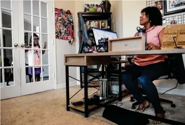  ?? Photos by Brett Coomer / Staff photograph­er ?? Employment attorney Jamila Brinson logs on to her computer as her daughter peeks through the door at home in Pearland. Brinson has returned to the Jackson Walker law firm’s office in downtown Houston.