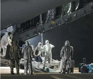  ?? PHOTO AFP ?? Des passagers prennent leurs bagages tandis qu’ils débarquent d’un avion d’Ankara en Turquie, après avoir été rapatriés de la ville de Wuhan, l’épicentre du coronaviru­s.