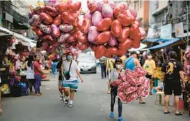 ?? AP ?? Women sell heart-shaped balloons at a flower market Monday in Manila, Philippine­s. Prices of flowers have increased because of the high demand expected for Valentine’s Day.