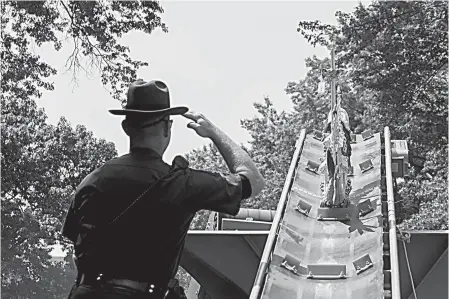  ?? AP Photo/Mary Altaffer ?? A New York State Environmen­tal Conservati­on officer salutes as an ivory sculpture rolls up a conveyor belt into a crusher Thursday at Central Park. The New York State Department of Environmen­tal Conservati­on destroyed illegal ivory confiscate­d through...