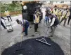  ?? BOB ANDRES/ROBERT. ANDRES@AJC.COM ?? After some instructio­n, Mayor Andre Dickens (right) tries his hand at repairing a pothole with members of the “pothole posse.”