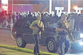  ?? [ADAM ROGAN/THE JOURNAL TIMES VIA THE ASSOCIATED PRESS] ?? In this Aug. 25 photo, Kyle Rittenhous­e, left, with backward cap, walks along Sheridan Road in Kenosha with another armed civilian. Prosecutor­s on Thursday charged Rittenhous­e, a 17-yearold from Illinois, in the fatal shooting of two protesters and the wounding of a third in Kenosha, Wisconsin, during a night of unrest following the weekend police shooting of Jacob Blake.