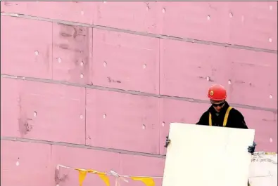  ?? AP/AMY SANCETTA ?? A worker labors last month on the roof of a commercial building going up in Cleveland. A drop in commercial building projects caused a dip in constructi­on spending in January.