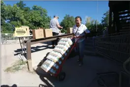  ?? CEDAR ATTANASIO — THE ASSOCIATED PRESS ?? Barrios Unidos President Lupe Salazar pushes a dolly filled with canned food ahead of a food drive in Chimay, New Mexico, on Thursday.